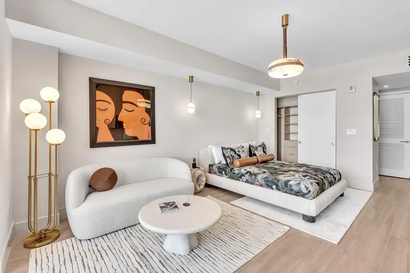 Living area with sofa, coffee table and bed, seen from the entry